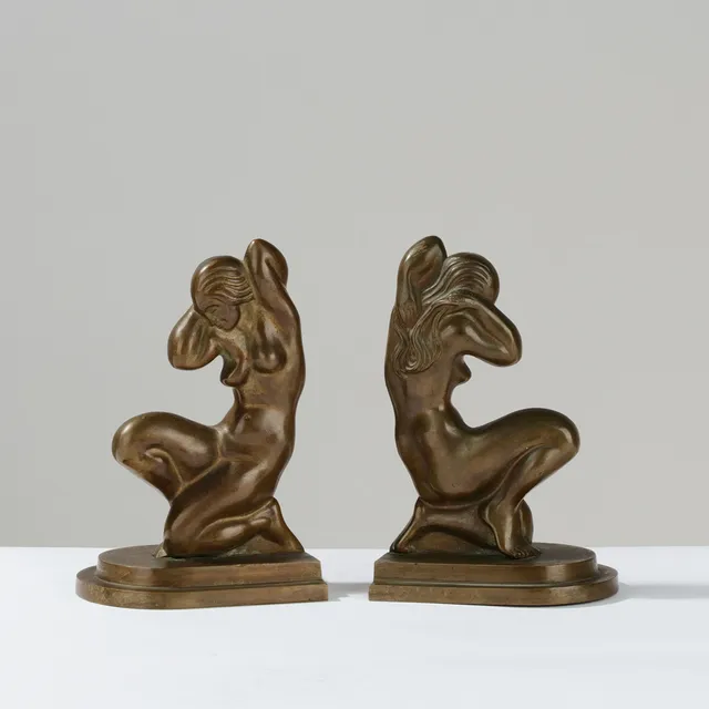 TINOS: Et par tunge bogstøtter af patineret bronze i Art Deco stil, begge dekoreret med skulptur af nøgen kvinde, Danmark, 1930/40'erne, (2).