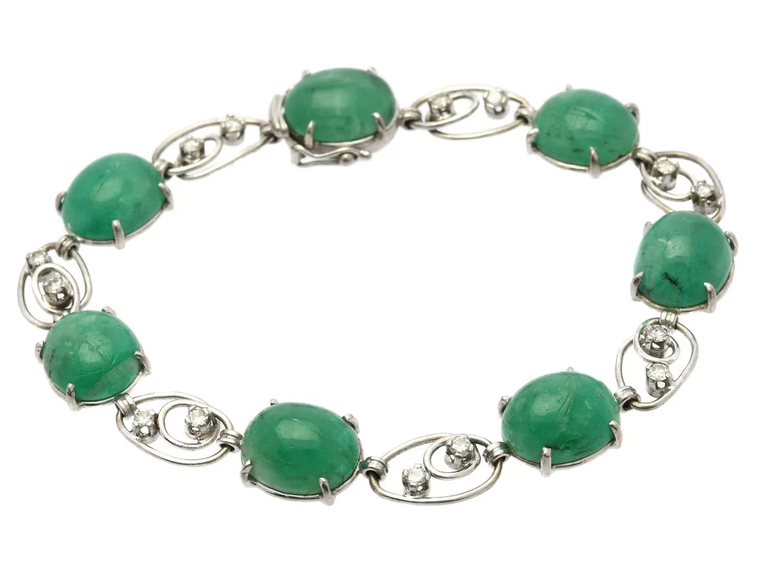 ARMBAND, 18K vitguld, cabochonslipade smaragder, briljantslipade diamaner ca 0,50 ctv, ca W-Cr/P, Atelier Ajour, Stockholm 1957, längd 19 cm, vikt 18,4 g, smargaderna med skador och nagg. — Smycken/Armband — Kaplans