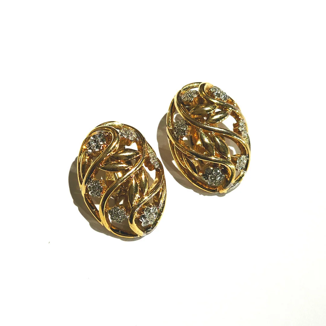 NINA RICCI. Grandes pendientes ovalados en metal dorado y circonitas formando flores. — Earrings — Arce Auctions