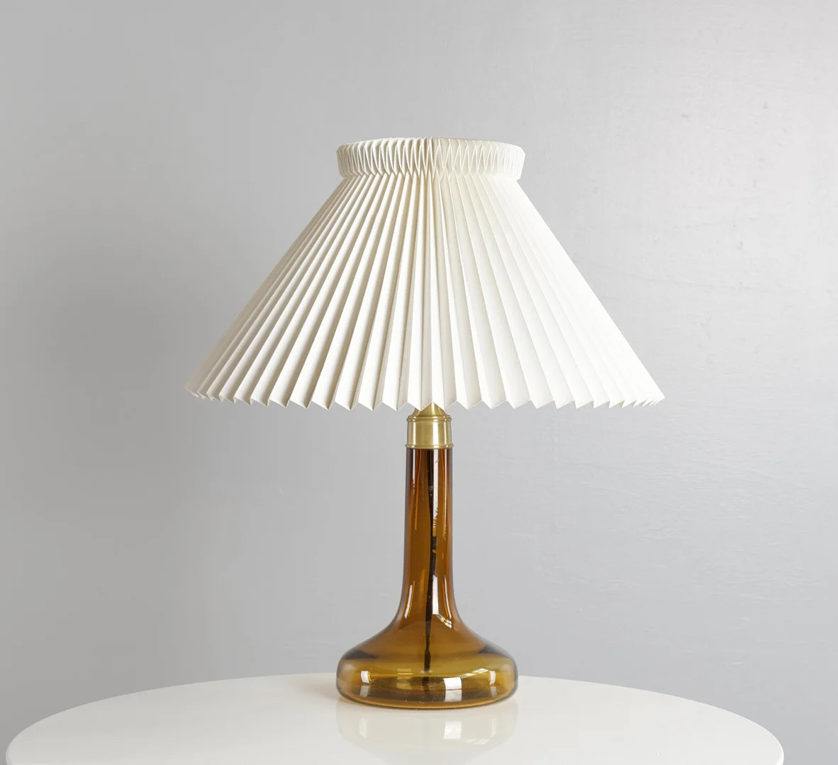 GUNNAR BIILMANN PETERSEN. Bordlampe af ravfarvet glas monteret med Le Klint skærme. Udført hos Holmegaard Glasværk for Le Klint. — Table Lamps — Woxholt Auktioner