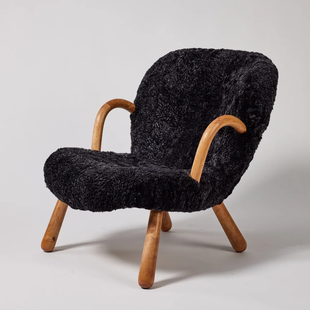 ARNOLD MADSEN. fåtölj, "Muslingestolen / Clam Chair", formgiven 1953, stoppad och klädd sits i fårskinn med detaljer i form av knappar, ben och armlän i björk, tidigare tillskriven Philip Arctander. — Armchairs & Chairs — Stockholms Auktionsverk Fine Art