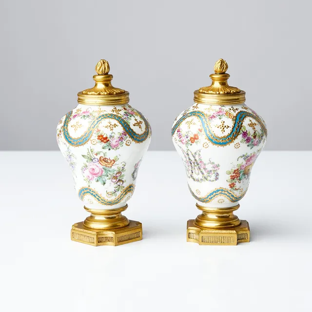 URNOR, 1 par, polykromt bemålade med bland annat motiv av blomstergirlanger, delvis förgyllda, fotplatta samt lock i förgylld mässing, möjligen Frankrike, 1800-talets andra hälft.