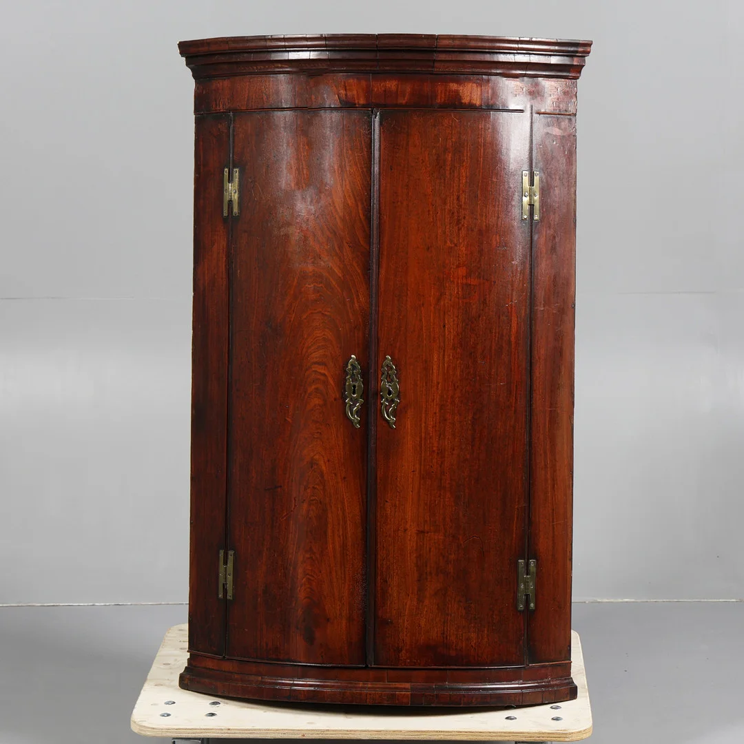 A GEORGE III MAHOGANY BOW FRONT HANGING CORNER CUPBOARD. — Cupboards, Cabinets & Shelves — Bishop & Miller