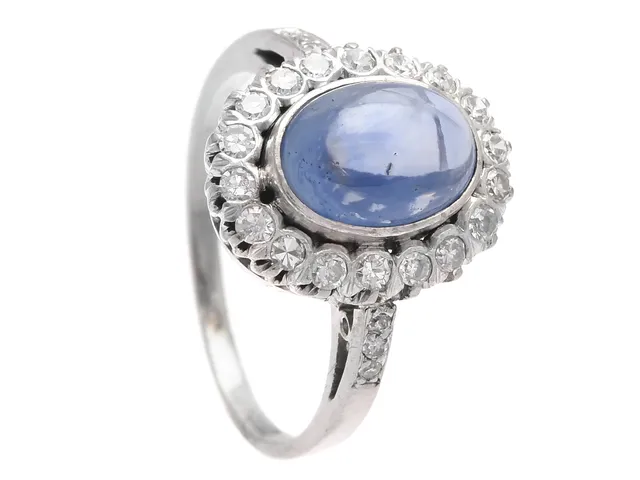 CARMOSÉRING, 18K vitguld, blå safir, 24 åttkanter ca 0,54 ctv ca TW-Ca/VS-P, stl 18 mm, vikt 5,7 g, 4 diamanter med nagg, några diamanter med inneslutningar som når ytan.