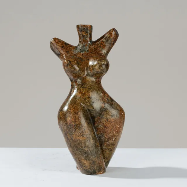 Skulptur af frodigt kvindetorso med brede hofter og struttende barm, udført i flerfarvet stenart af ubekendt formgiver.