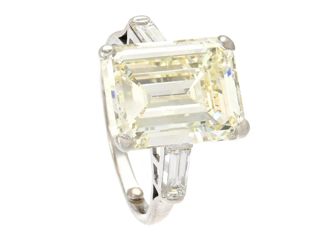 THEO FENNELL, trestensring, platina, smaragdslipad diamant ca 8,48 ct, ca Ca(M)/VS1, baguettslipade diamanter ca 0,60 ctv, stl ca 16,5 mm, vikt 6,1 g, storleksminskande kulor i ringskenan, mittstenen rör sig något i fattningen och har nagg, ena sidostenen är skadad. — Smycken/Trestensring — Kaplans