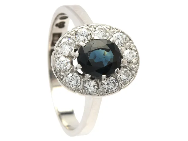 CARMOSÉRING, 18K vitguld, ovalslipad blå safir ca 0,78 ct, 10 briljant- och äldre briljantslipade diamanter ca 0,46 ctv, ca TW-TCr(G-I)/SI, stl 17 mm, vikt 4,6 g, safiren har nagg vid bordet, en diamant med nagg vid bordet och en med nagg på kulett.