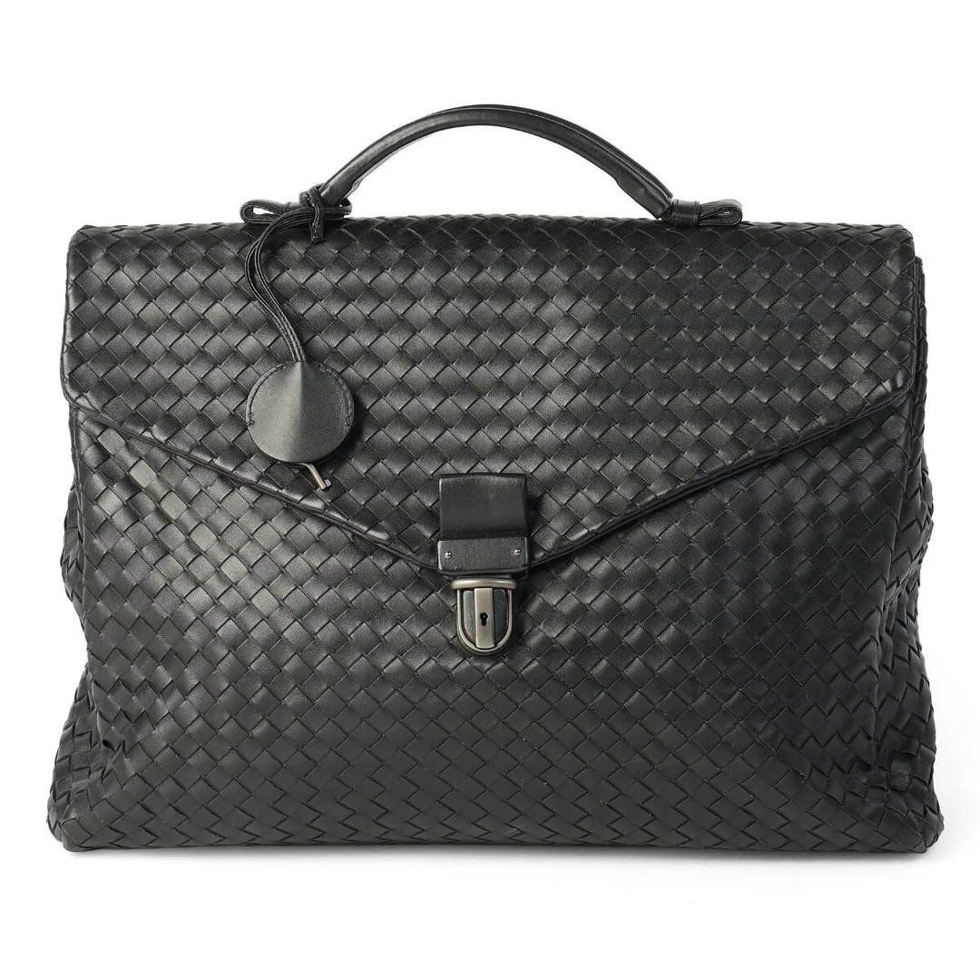 A briefcase/bag of black woven leather with silver tone hardware, short handle, one exterior zipped pocket and two compartments with black fabric lining. Accompanied by a key. H. 28 x W. 38 x D. 8 cm. — Designer Handbags & Fashion/Designer Handbags — Bruun Rasmussen