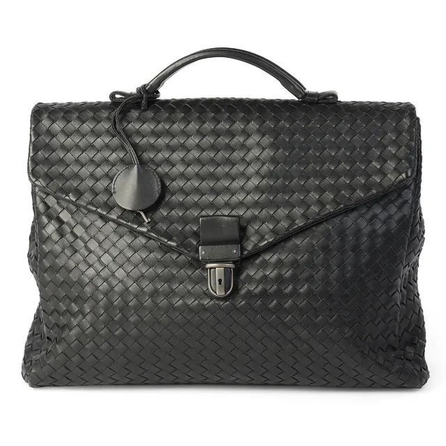 A briefcase/bag of black woven leather with silver tone hardware, short handle, one exterior zipped pocket and two compartments with black fabric lining. Accompanied by a key. H. 28 x W. 38 x D. 8 cm.