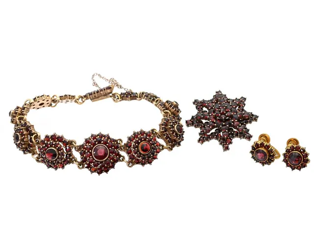 SMYCKESET, örhängen, brosch och armband, gulmetall, granater, örhängen höjd 12 mm, brosch diameter ca 30 mm, armband längd 18 cm,lvikt 29,3 g, örhängen med skruvmekanism, armband saknar en sten nära låset och har någon sten med mindre nagg.