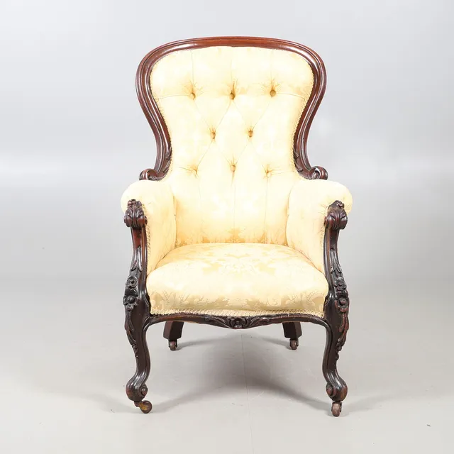 A VICTORIAN CARVED MAHOGANY BUTTON BACK GENTLEMANS ARMCHAIR.