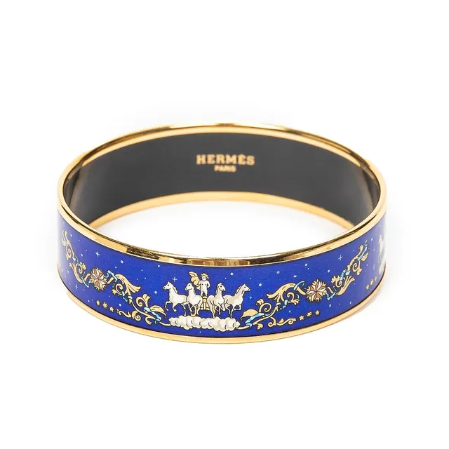 A bangle set with a blue enamel motif, mounted in gold coloured metal. Weight app. 32.9 g. W. Inner diam. app. 6.5 cm.