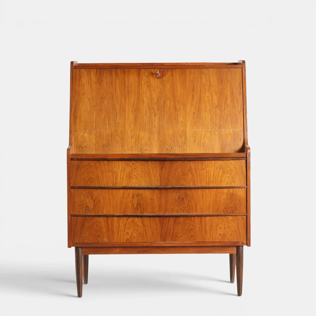 Chatol af palisander, front med tre skuffer, herover nedfældig klap bag hvilke skuffer og hylder, runde tilspidsede ben. Danmark, 1960'erne. — Cupboards, Cabinets & Shelves — Woxholt Auktioner