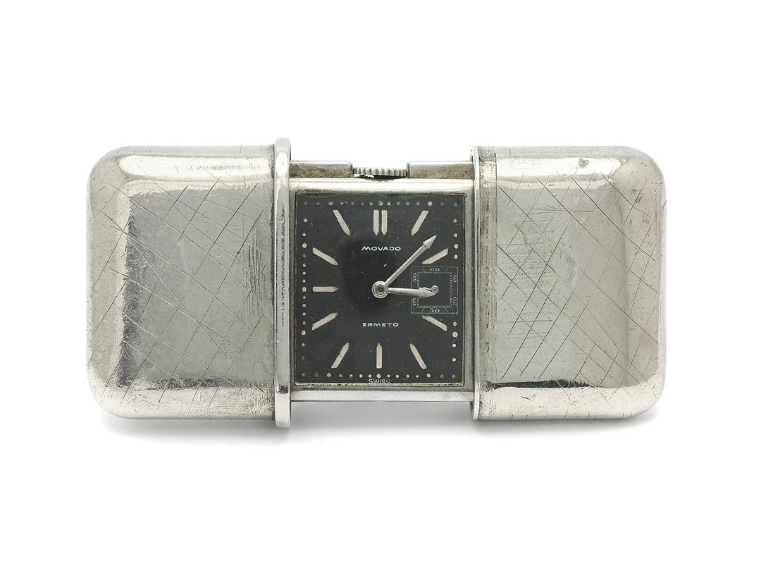 MOVADO, Ermeto, reseur, 50 x 35 (75) mm, Boett nr. 511106, vitmetall, manuell, plexiglas, liten sekundvisare, skadad urtavla, defekt uppdragsfunktion, skadad boett, gravyr, ca 1930. — Klockor/Movado — Kaplans