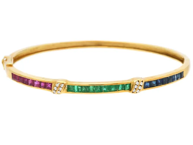 ARMRING, 18K guld, carréslipade rubiner, smaragder, safirer, diamanter 0,06 ctv, 58 x 52 mm, vikt 12 g, några diamanter med skador och nagg.