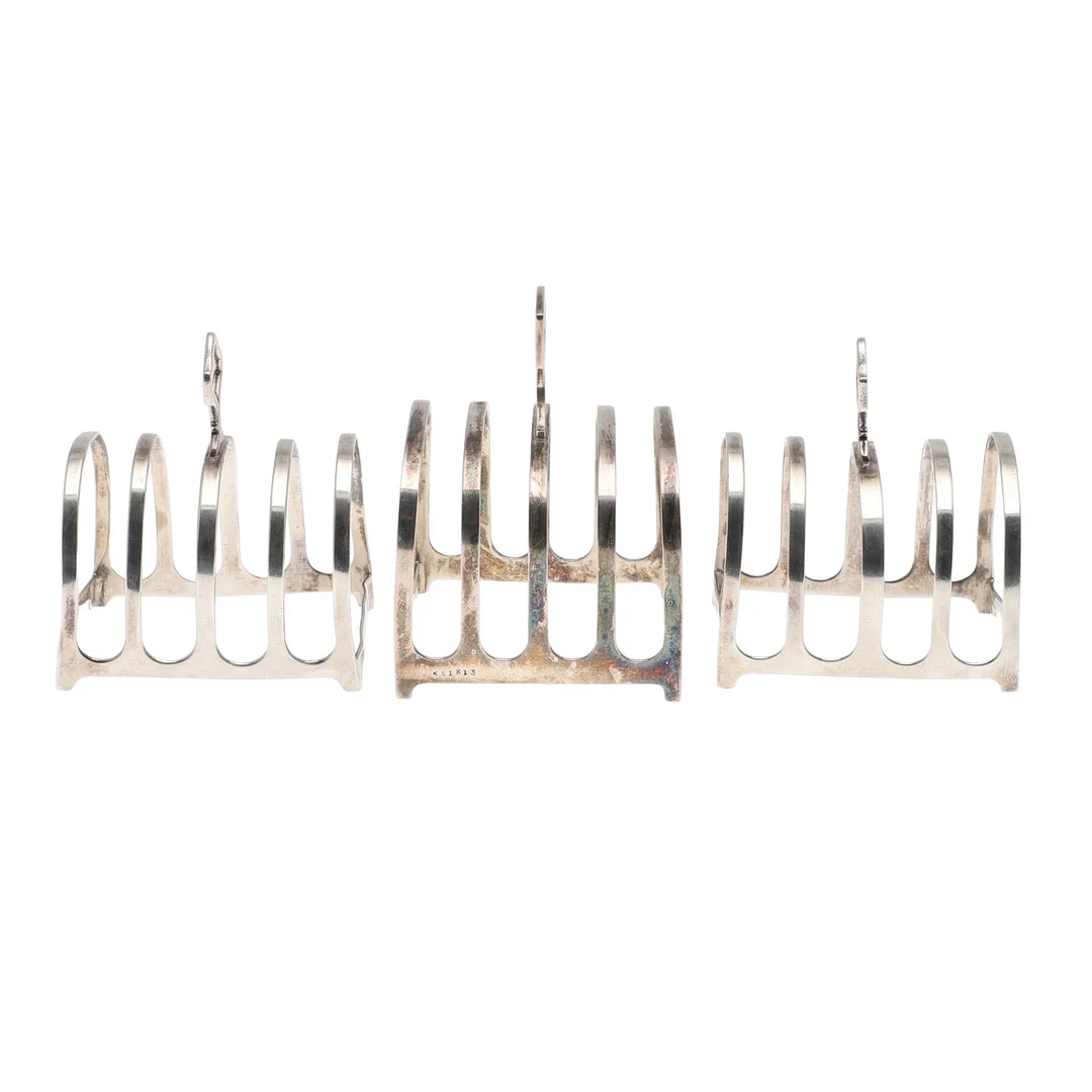 THREE EARLY 20TH CENTURY SILVER FOUR PLACE TOAST RACKS. — Silver — Lawrences Auctioneers