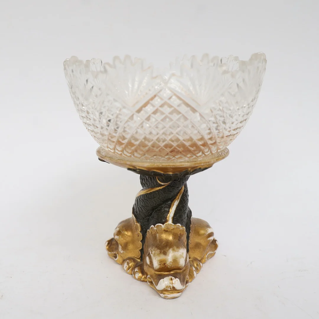 SKÅL PÅ FOT, empirestil, 1800-1900-tal, fot föreställande delfiner i bemålad och förgylld keramik. Upptill med slipad skål i glas. — European — Falun Auktionsbyrå