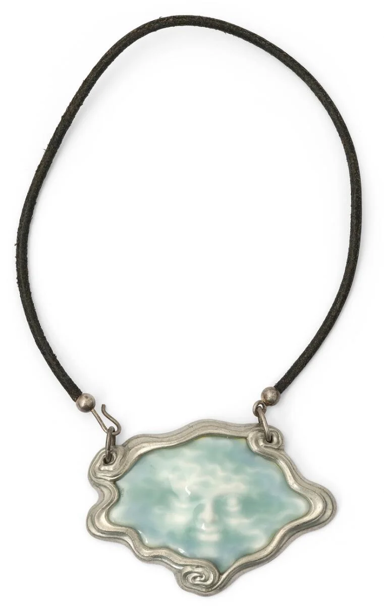 A necklace and pendant in pewter and procelain set with “Seaface” in blue glacing. Pendant 6.2 × 8.7 cm. Necklace L. app. 60 cm. Arje Griegst for Royal Copenhagen. — Jewellery/Necklaces & pendants — Bruun Rasmussen