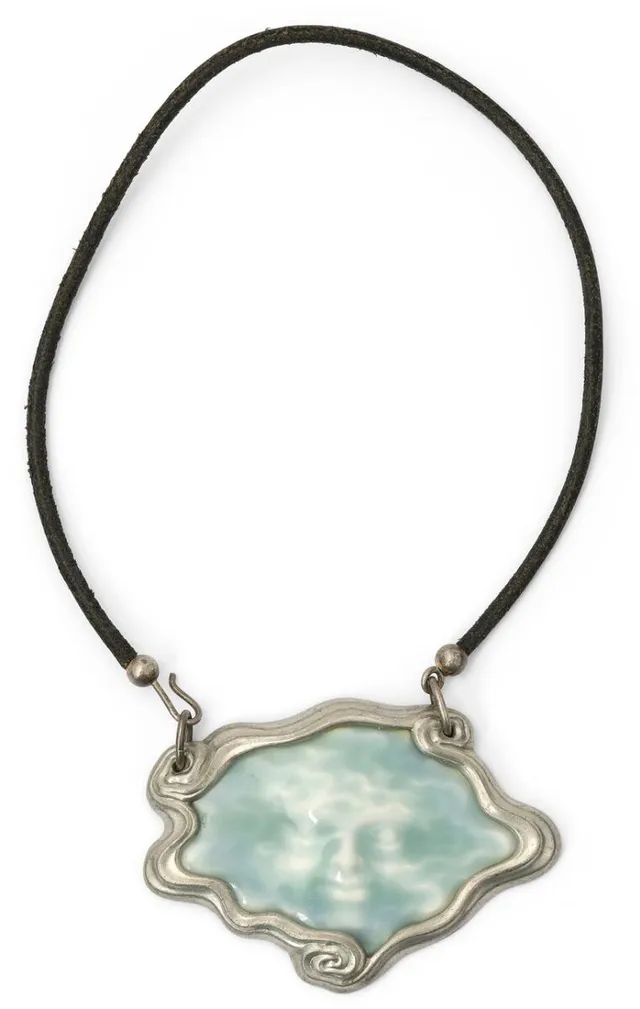 A necklace and pendant in pewter and procelain set with “Seaface” in blue glacing. Pendant 6.2 × 8.7 cm. Necklace L. app. 60 cm. Arje Griegst for Royal Copenhagen.
