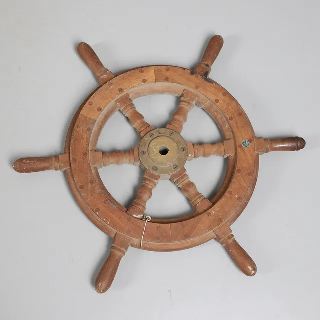 A DECORATIVE SHIPS WHEEL.