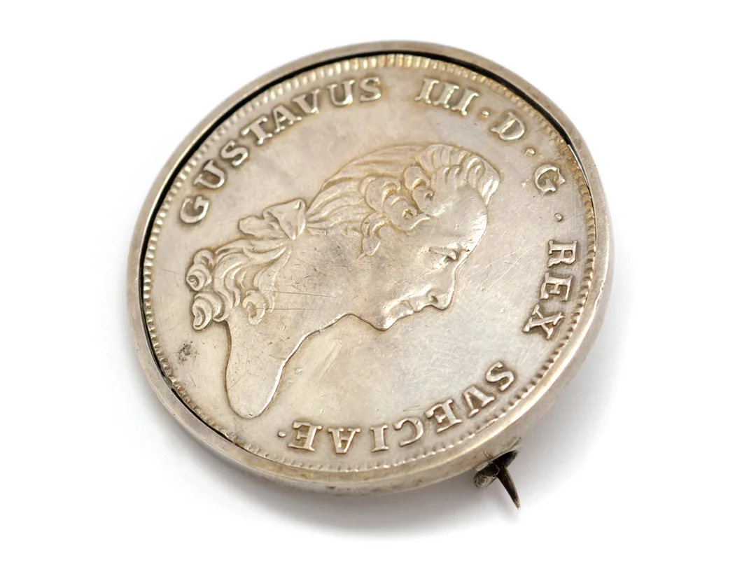 BROSCH, silver, infattad Riksdaler, 1781, Gustav III, myntet skadat av fattningen, total vikt 35,1 g. — Smycken/Brosch — Kaplans