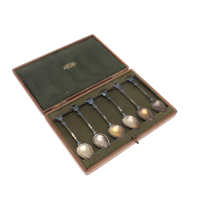 A CASED SET OF SIX EDWARDIAN ARTS AND CRAFTS SILVER AND ENAMELLED TEA SPOONS.