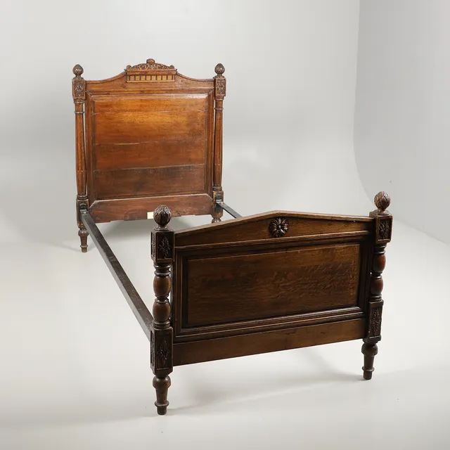 A LATE VICTORIAN CARVED OAK SINGLE BED.