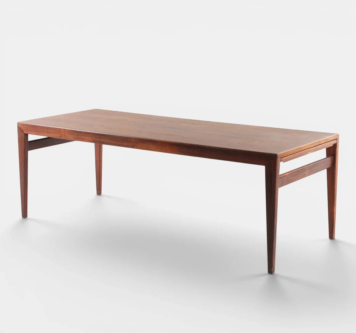 JOHANNES ANDERSEN. Sofabord af palisander, ene ende med udtræksplade beklædt med sort formica, den anden ende med udtræksplade finéret med palisander, tilspidsede ben. Udført hos CFC, Silkeborg. Danmark, 1960'erne. — Coffee Tables — Woxholt Auktioner