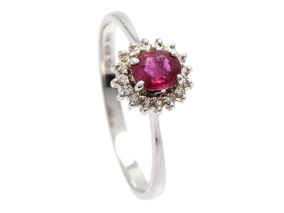 CARMOSÉRING, 18K vitguld, 1 ovalslipad rubin ca 0,35 ct, 16 briljantslipade diamanter ca 0,08 ctv, stl 17,50 mm, vikt 1,9 g, nagg på rubin och diamanter, rubin med inneslutning som når ytan. — Smycken/Carmoséring — Kaplans