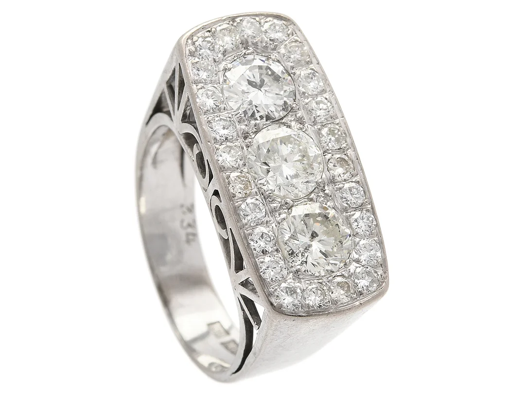 RING, 18K vitguld, 3 briljantslipade diamanter ca 1,65 ctv ca Cr-TCa(J-K)/P1, 24 briljantslipade diamanter ca 0,72 ctv, ca W-Ca/SI-P, Stockholm 1966, stl 17,75 mm, vikt 9,3 g, två små diamanter skadad. — Smycken/Ring — Kaplans