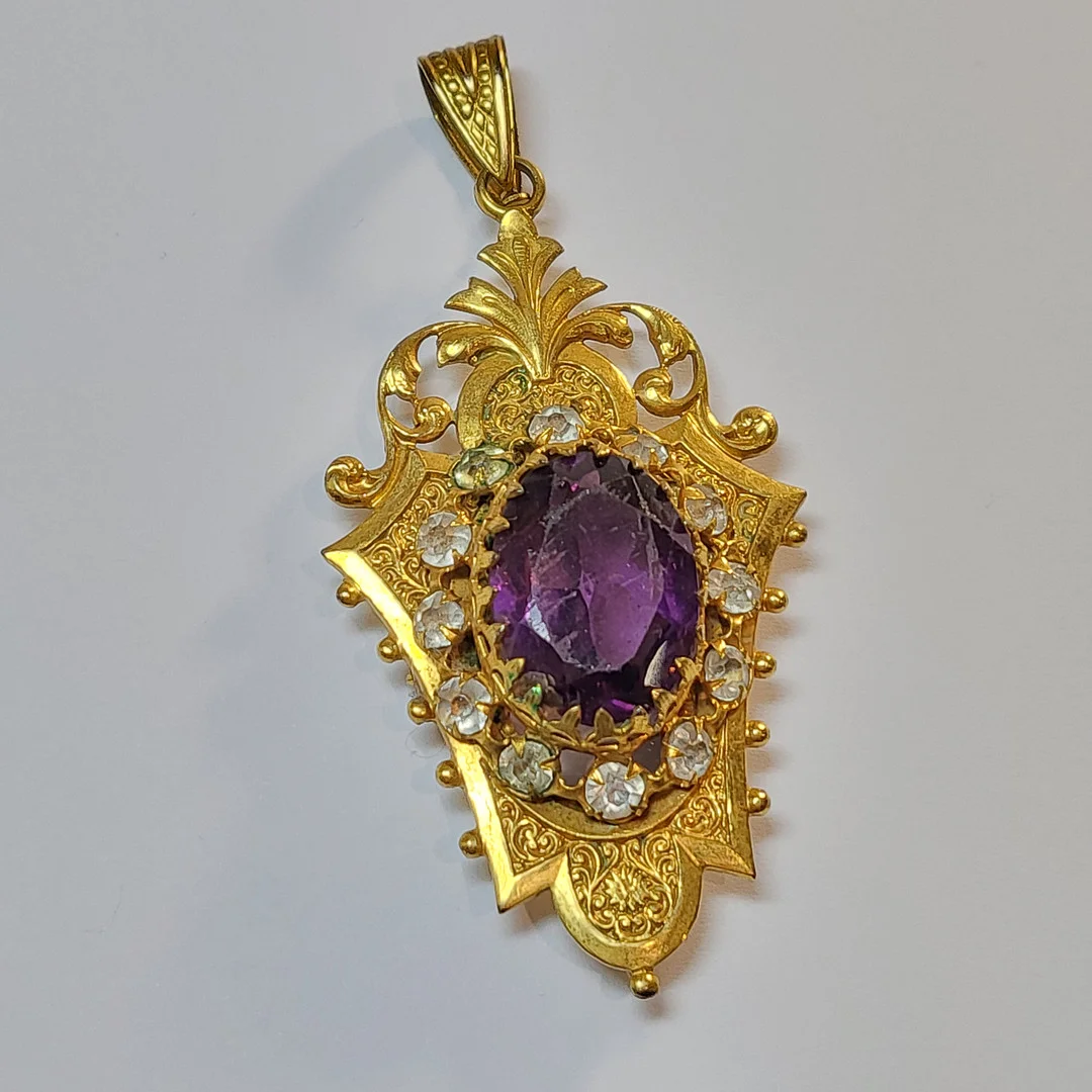 COLGANTE DE BISUTERÍA ANTIGUA, GUARDA FOTOS EN METAL DORADO Y PIEDRA DE COLOR AMATISTA. — Brooches & Pendants — Barcelona Auctions