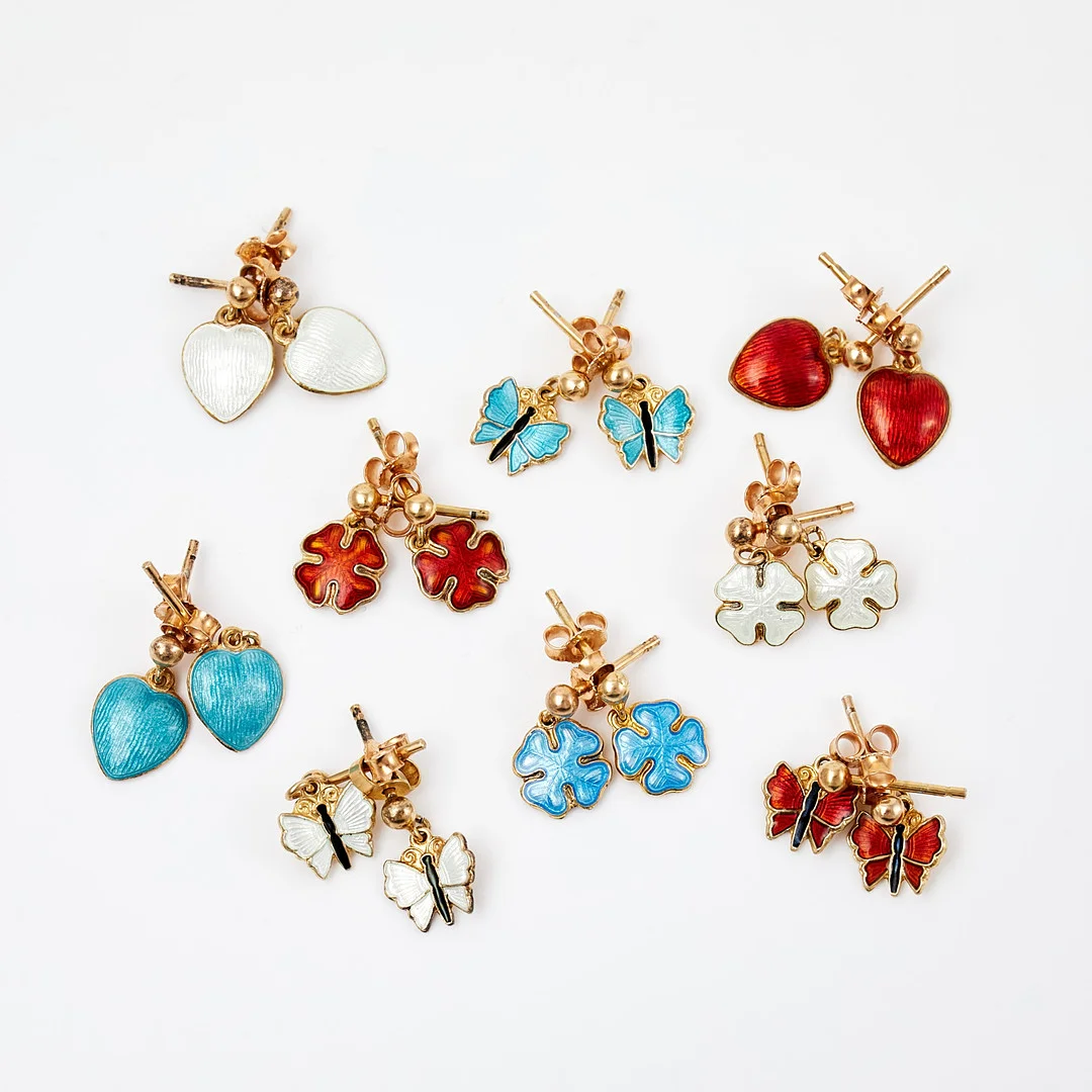 AKSEL HOLMSEN. Örhängen, 9 par, förgyllt silver, guillocherad emaljdekor, i form av fjärilar, hjärtan samt fyrklöver. — Earrings — Stockholms Auktionsverk Sickla