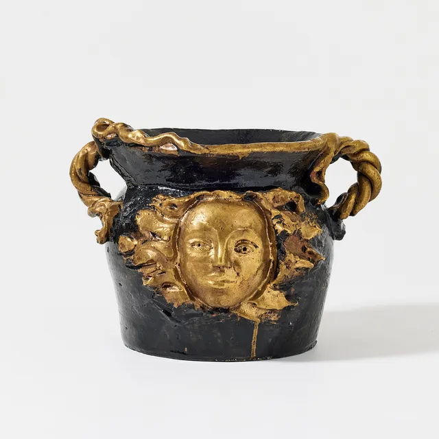 HERTHA HILLFON. ”Solguden”. urn, own studio, earthenware, relief decoration of a face and braided handles, glazed in black with gold decoration.