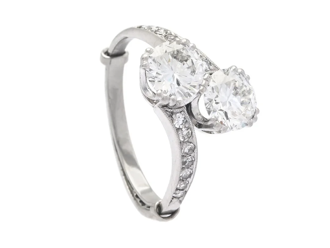 SYSKONRING, platina, 2 äldre briljantslipade diamanter ca 2,15 ctv enligt gravyr, ca TW(F-G)/VVS, 14 åttkantslipade diamanter ca 0,16 ctv, stl 18,25 mm, vikt 5,9 g, inre ringskena, diamanterna med natural och extrafasett vid rondist. — Smycken/Ring — Kaplans