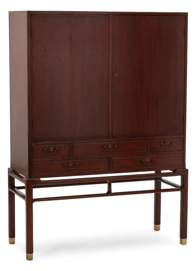 Freestanding mahogany cabinet with brass “shoes”. Profiled front with two doors and five drawers with brass handles. Interior resp. with shelves and pull-out trays. Made by cabinetmaker William Christensen for retailer Illums Bolighus. H. 150 cm. W. 107.5 cm. D. 45 cm.