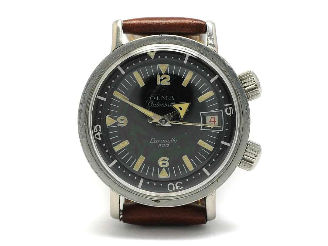 OLMA, Caravelle 200, Cal AS 1902/18, Boett nr. 669, herrur, 36 mm, stål, automatisk, plexiglas, datum, vridbar innerring, skadad urtavla (6/10), gravyr, läderband, ca 1965. — Klockor/Olma — Kaplans