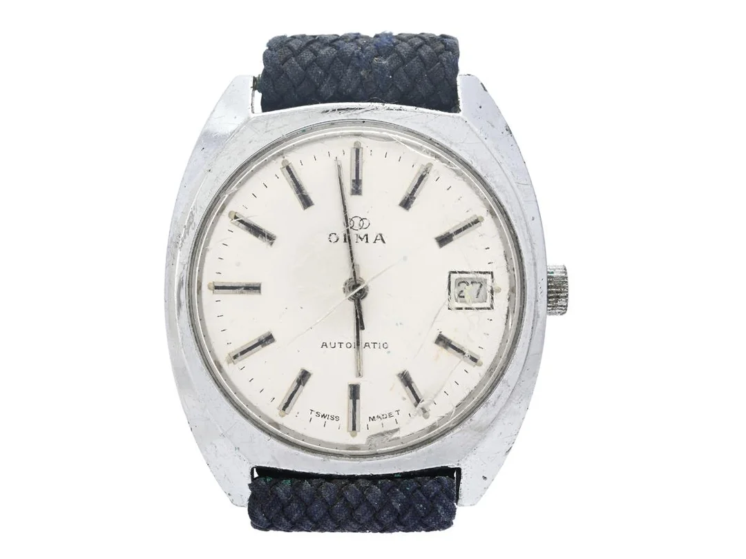 OLMA, herrur, 35,5 mm, Boett nr. 05200-3, vitmetall, automatisk, plexiglas (skadat), datum, skadad urtavla, defekt, Perlonband, ca 1970. — Klockor/Olma — Kaplans