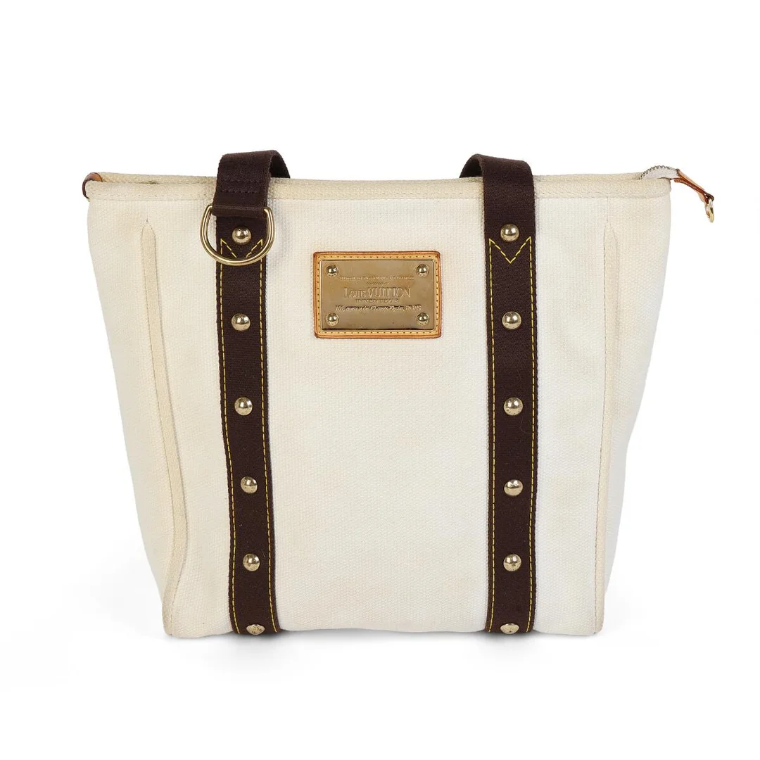 An “Antigua Cabas” shoulder bag of white and brown canvas with gold-tone hardware, featuring two handles, one compartment with a zipper closure, an interior pocket, and brown/white striped canvas lining. H. 34 × W. 36 × D. 10 cm. 2005. — Designer Handbags & Fashion/Designer Handbags — Bruun Rasmussen