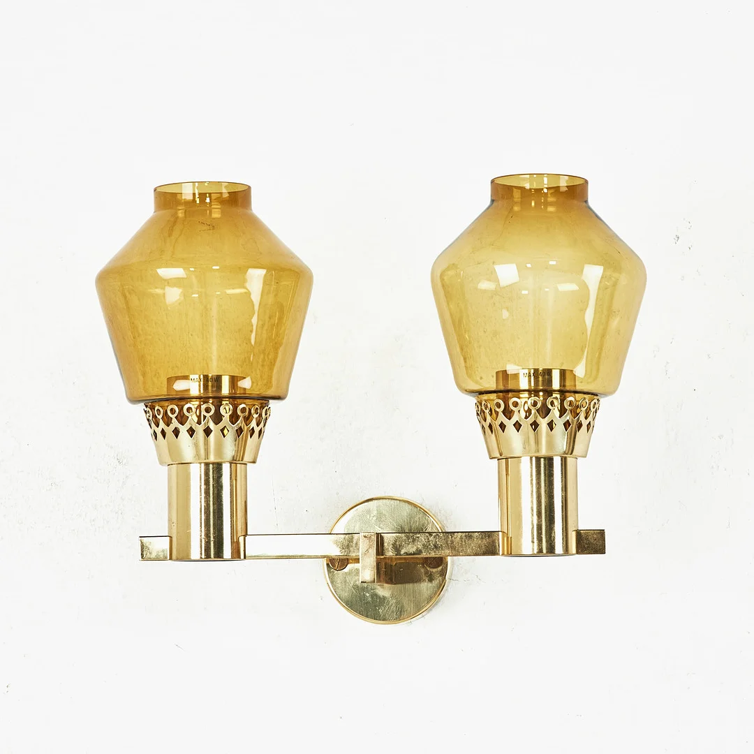 HANS-AGNE JAKOBSSON. Väggarmatur, modell V 323/2, Markaryd 1960-/70-tal, för två ljuspunkter, mässing, kupor i cognacsfärgat glas. — Wall Lights — Stockholms Auktionsverk Magasin 5