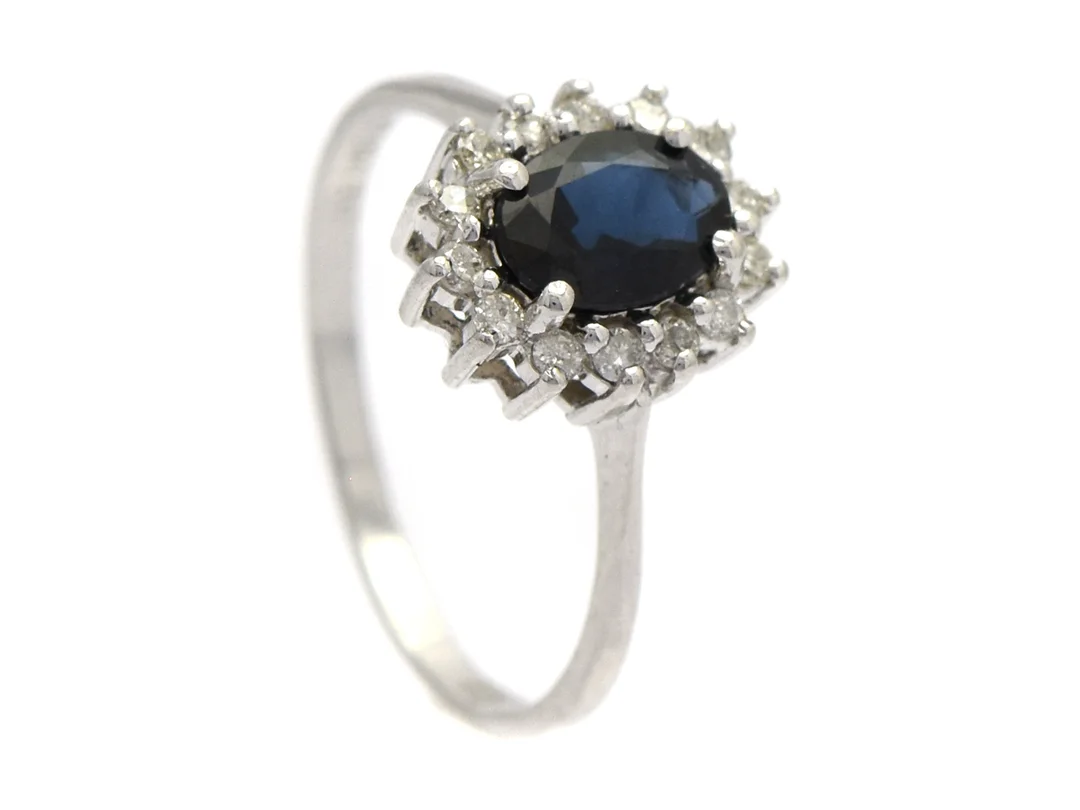 CARMOSÉRING, 18K vitguld, blå safir ca 1,05 ct, 14 briljantslipade diamanter ca 0,20 ctv, stl 17,25+ mm, vikt 2,5 g, 4 diamanter med nagg/skador. — Smycken/Carmoséring — Kaplans