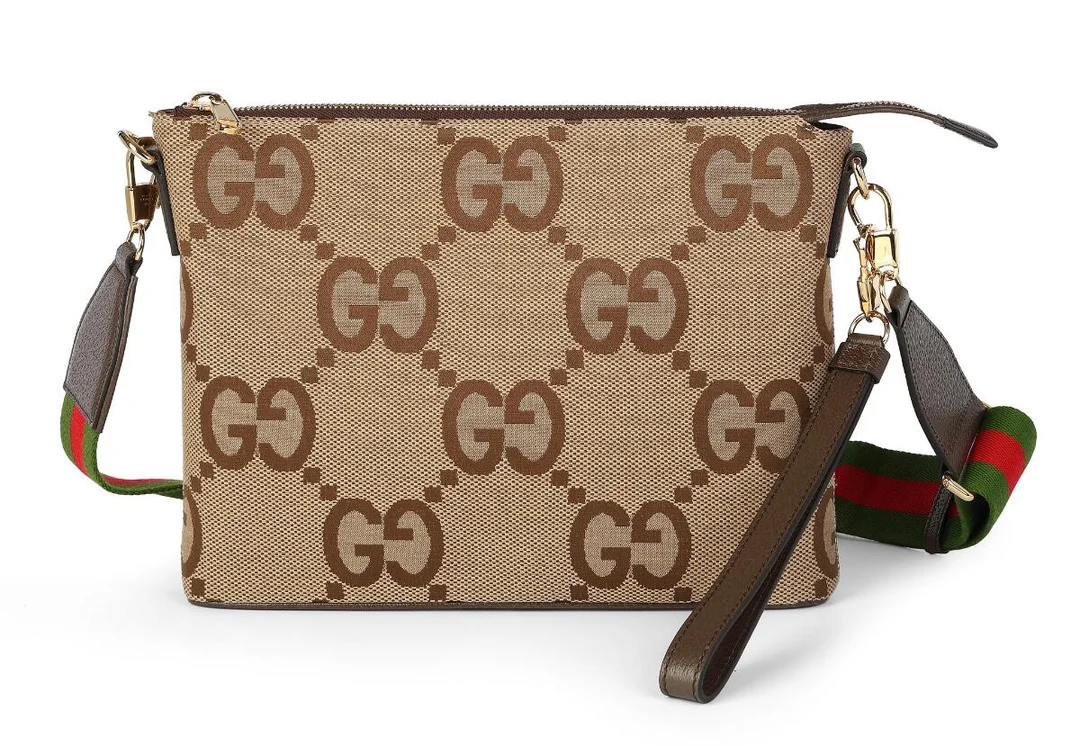 A “Jumbo GG Pouch” of brown monogram canvas with brown leather trimmings, gold tone hardware, detachable and adjustable shoulder strap of canvas, a main zipped compartment with an interior zipped pocket and light coloured fabric lining. Accompanied by detachable wristlet. H. 23 x W. 30 x D. 5 cm. — Designer Handbags & Fashion/Designer Handbags — Bruun Rasmussen