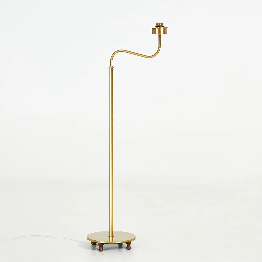 JOSEF FRANK. Golvlampa med svängd arm, "Lilla kamelen", ställbar i höjd. på fyra träfötter, märkt Svenskt Tenn 2568, mässing. — Floor lights — Stockholms Auktionsverk Sickla