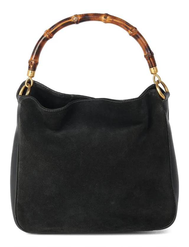 A “Bamboo” bag of black suede and leather with a bamboo handle and gold-tone hardware, featuring a single compartment with snap-button closure, one interior zippered pocket, and grey microfiber lining. H. 26 × W. 30 × D. 11 cm.