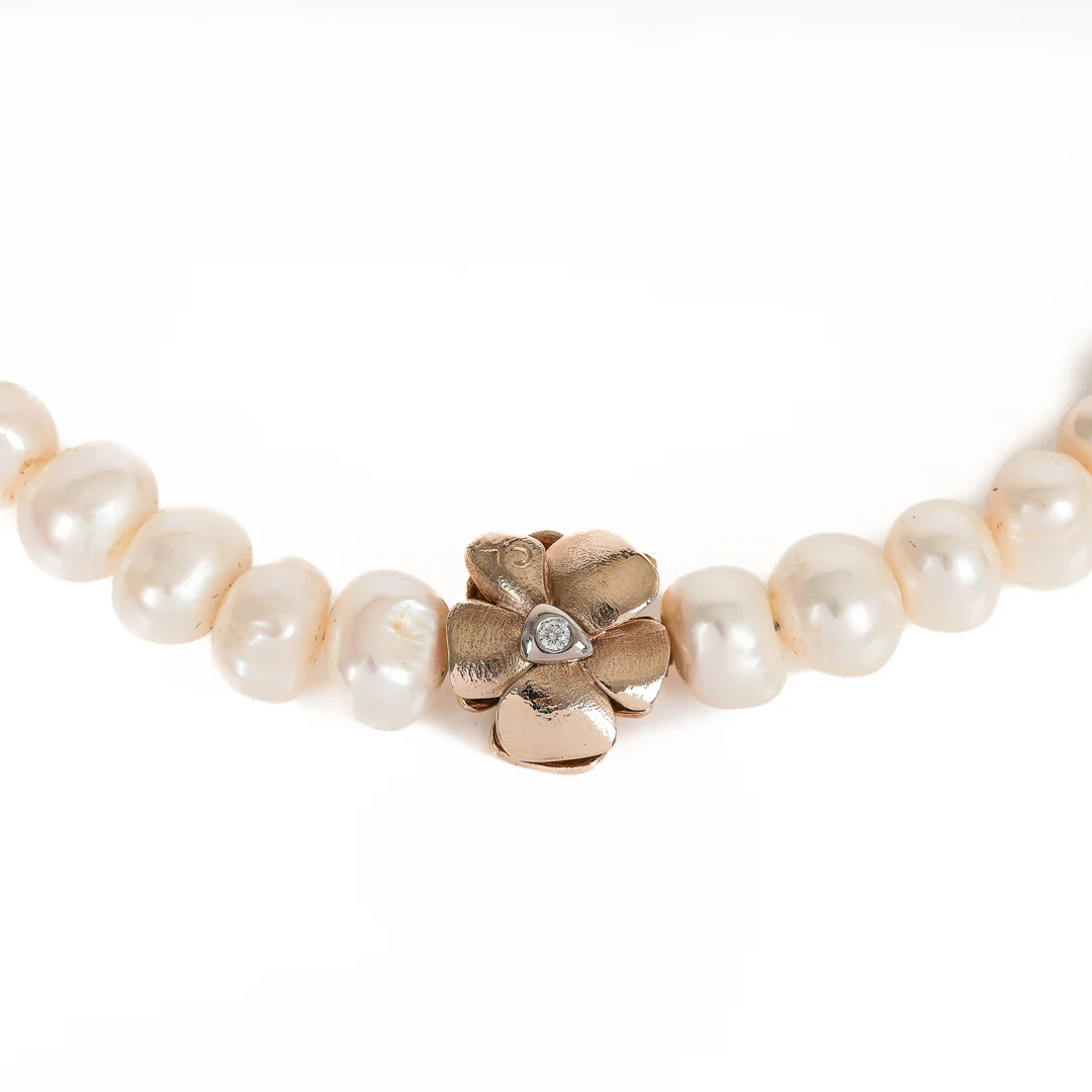 Ole Lynggaard (b. 1936): A small 'Flower' clasp of 14k gold and white gold with a pearl necklace. (2) — Jewellery/Necklaces, pendants — Lauritz