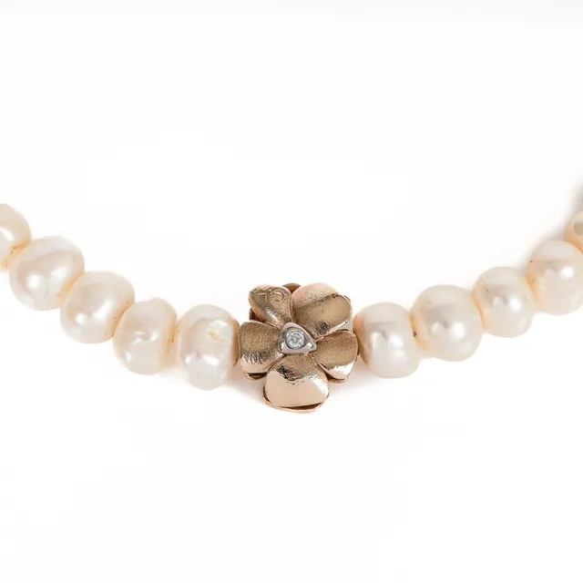 Ole Lynggaard (b. 1936): A small 'Flower' clasp of 14k gold and white gold with a pearl necklace. (2)