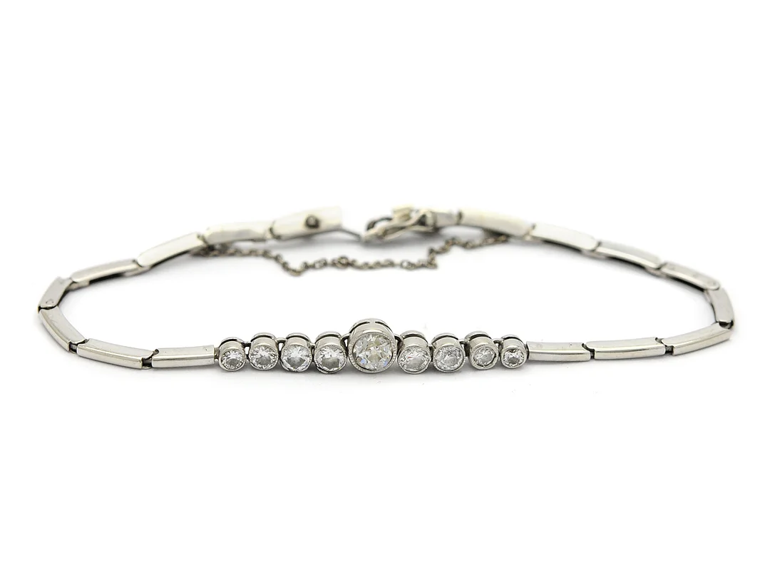 ARMBAND, 18K vitguld, 9 diamanter doserade ca 0,05 - 0,30 ct, ca 0,88 ctv, (mittsten + 1 sidosten gammalslipade, övriga mediumslipade), ca W/VS-SI, Malmö 1939, längd 16,5 cm, vikt 6,7 g, lås defekt. — Smycken/Armband — Kaplans