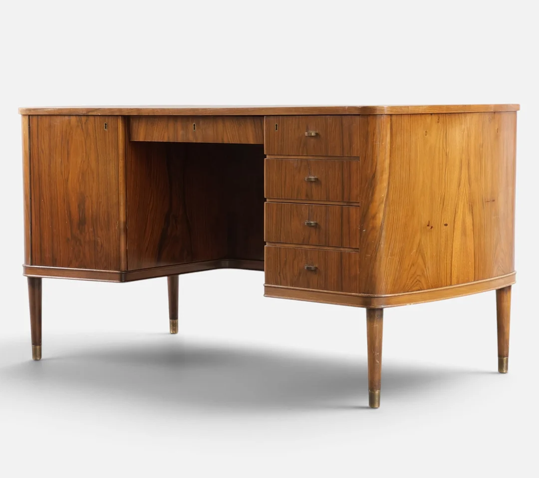 Fritstående skrivebord af nød, front med skuffer og låge med greb af messing, runde tilspidsede ben med 'sko' af messing. Danmark, 1940-50'erne. — Desks — Woxholt Auktionshus
