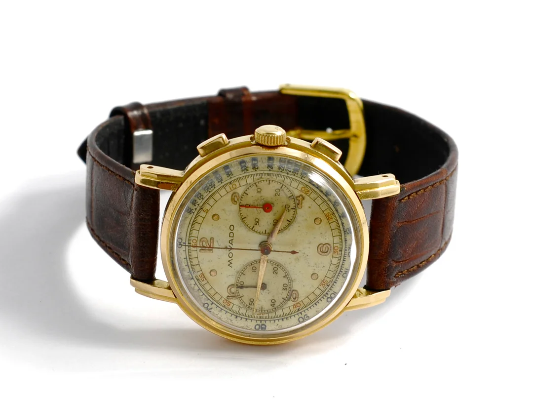MOVADO, kronograf, Cal 90 M, nr. A 99857, nr. R 9023, herrur, 34 mm, 18K guld, manuell, plexiglas, skadad urtavla, skadad boett, läderband, ca 1950. — Klockor/Movado — Kaplans