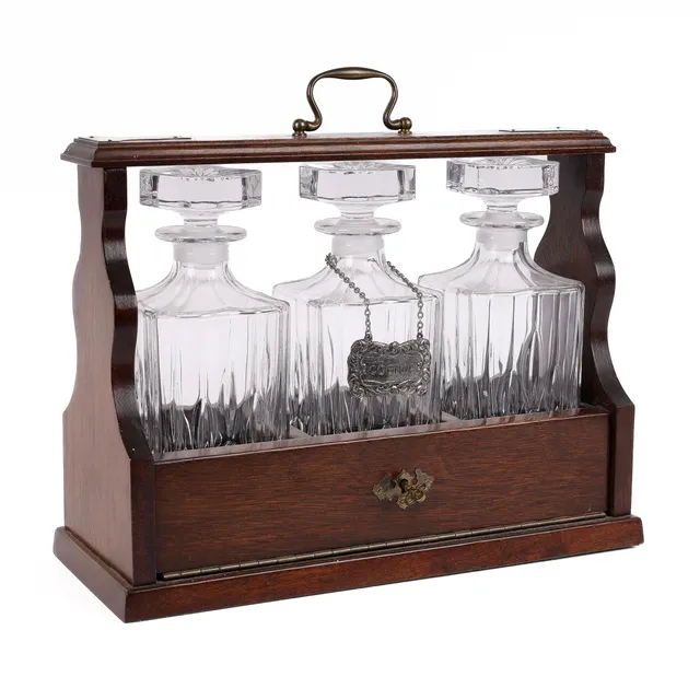 Tantalus of dark-colored wood, containing three polished carafes. Mid-20th century.