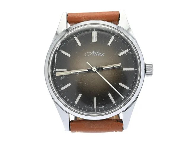NILAX, herrur, 34 mm, Boett nr. 11 213, vitmetall, manuell, plexiglas (skadat), skadad urtavla, läderband, ca 1970.